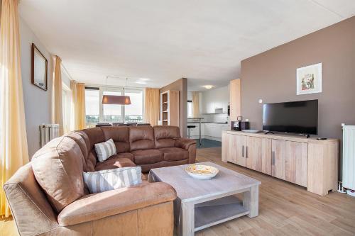 ein Wohnzimmer mit einem Sofa und einem TV in der Unterkunft Hello Zeeland - Appartement Port Scaldis 15-042 in Breskens