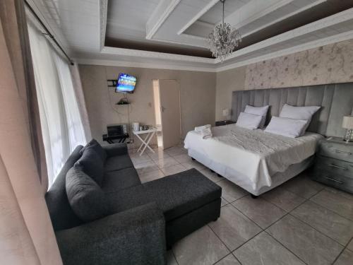 a bedroom with a bed and a couch and a tv at 016 Guest House in Vanderbijlpark