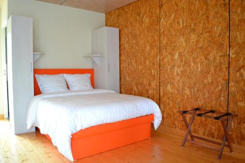 - une chambre avec un lit orange et un mur en bois dans l'établissement Domaine des Epines, à Coulanges-lès-Nevers