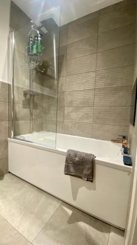 a bathroom with a bath tub with a towel on it at Modern 2 Bed Apartment/Free Parking/Near City/Self-Check In in Handsworth