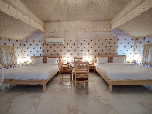 a bedroom with two beds and a table and chairs at Hill View Resort by Rudrakshi in Udaipur