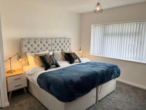 a bedroom with a large bed with a blue blanket at The Lambourne in Birstall
