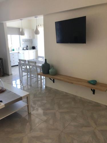 uma sala de estar com uma mesa e uma televisão na parede em Venetia apartment em Porto Heli