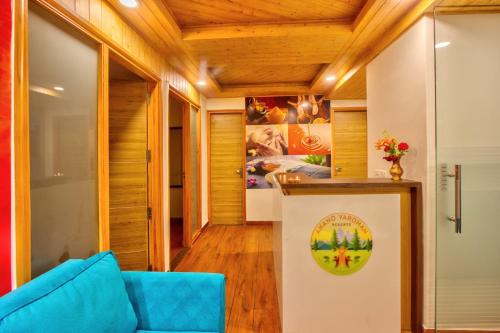 a living room with a blue couch and wooden ceilings at Anand Vardhan Resorts in Manāli