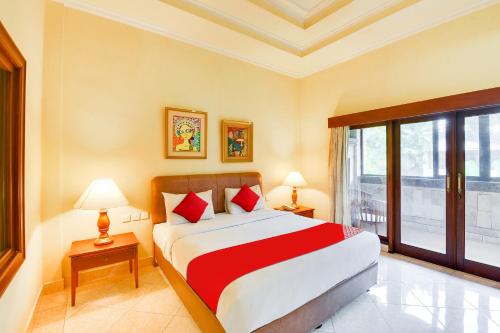 a bedroom with a bed and a large window at Super OYO Townhouse Oak Maxi Hotel Legian in Kuta