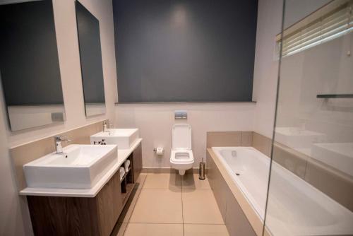 a bathroom with two sinks and a toilet and a tub at Stays With DMWA in Johannesburg