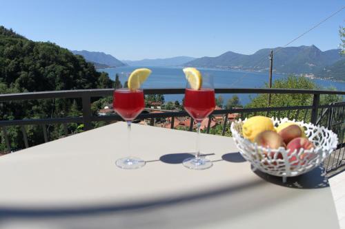 a table with two wine glasses and a basket of fruit at Casa Colmegna mit traumhaften See- und Bergblick in Luino