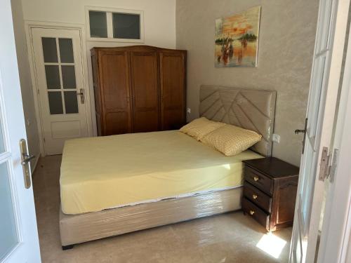 a bedroom with a bed with a wooden cabinet and a dresser at Appartement bord de mer et piscine en option in Tangier