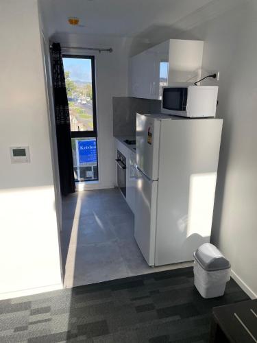 a kitchen with a white refrigerator and a microwave at Krishna Motel - Newly Built in Papakura in Auckland