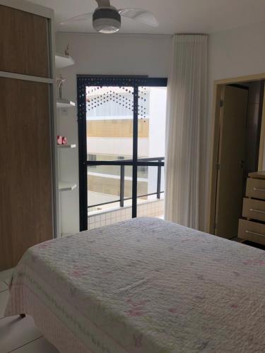 a bedroom with a bed and a door to a balcony at Apartamento Peracanga com Wi-Fi in Guarapari