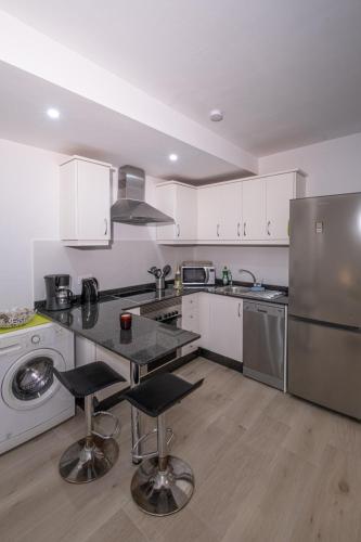 a kitchen with white cabinets and a stainless steel refrigerator at Casita Emma in Playa Blanca