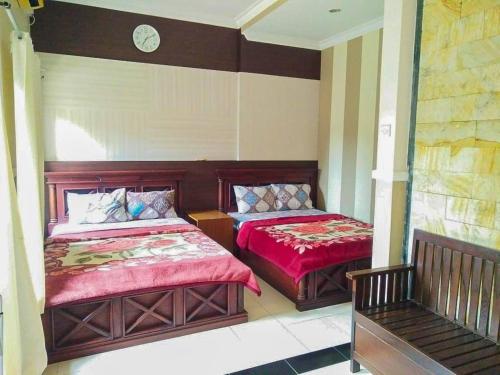 - une chambre avec 2 lits et une horloge murale dans l'établissement Hotel Abad Baru 1, à Pangandaran