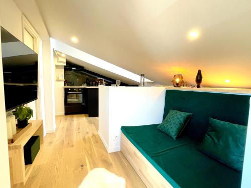 un salon avec un canapé vert dans une cuisine dans l'établissement Studio Climatisé sous les Toits à 100m de la place du Capitole, à Toulouse