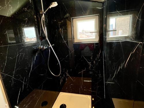La salle de bains noire est pourvue d'une douche et de toilettes. dans l'établissement Studio Climatisé sous les Toits à 100m de la place du Capitole, à Toulouse