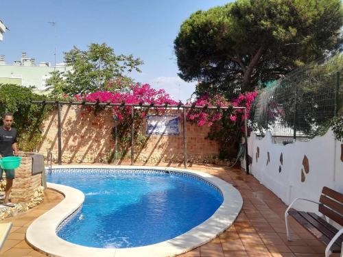 een zwembad in een tuin met roze bloemen bij Casa Marquesa in Punta Umbría