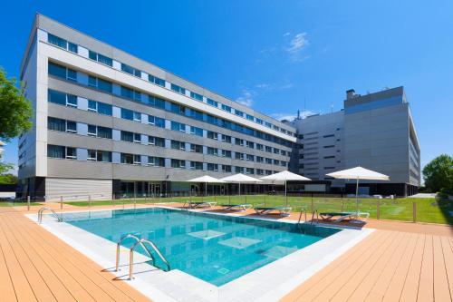 un hotel con piscina di fronte a un edificio di Axor Barajas a Madrid