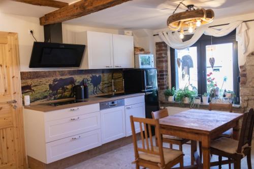 a kitchen with white cabinets and a table at Landhausstube in Kraftsdorf