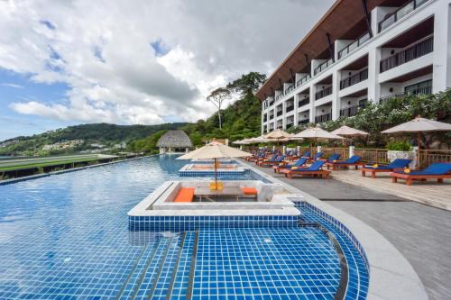 une piscine dans un hôtel avec des chaises et des parasols dans l'établissement Andamantra Resort and Villa Phuket - SHA Extra Plus, à Patong Beach