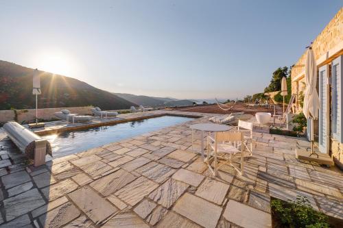a pool with chairs and a table on a stone patio at Patmosphere Luxury Escape Adults-Only in Patmos