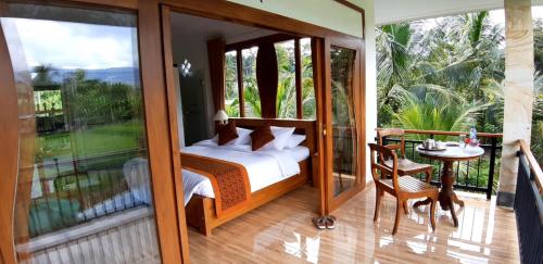 a bedroom with a bed and a balcony with a table at The Aroma Villa Munduk in Mayong