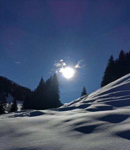 a snow covered hill with the sun in the sky at Pension Ferienwohnung Pirhofer in Kramsach