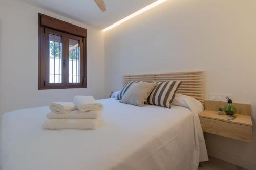 een witte slaapkamer met een groot bed met handdoeken erop bij Madera Negra in Córdoba
