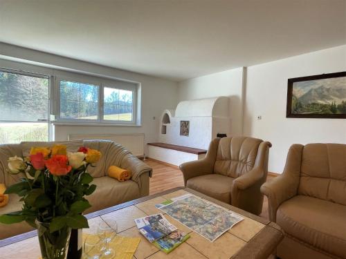 a living room with two couches and a table with flowers at Holiday Home Anger - ANB100 by Interhome in Angerberg