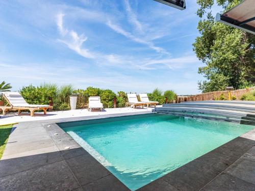 een zwembad met 2 ligstoelen in de tuin bij Holiday Home Indigo-Vue Mer et Piscine chauffée by Interhome in Saint-Brevin-les-Pins