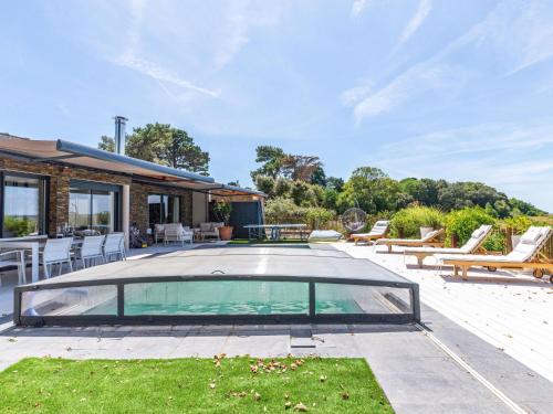 een zwembad met stoelen en een huis bij Holiday Home Indigo-Vue Mer et Piscine chauffée by Interhome in Saint-Brevin-les-Pins