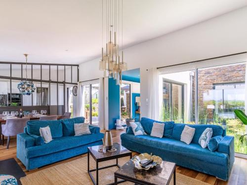 un salon avec des canapés bleus et une salle à manger dans l'établissement Holiday Home Indigo-Vue Mer et Piscine chauffée by Interhome, à Saint-Brévin-les-Pins