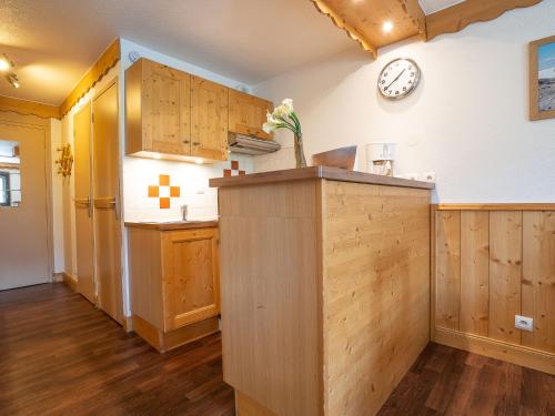 une cuisine avec des armoires en bois et une horloge au mur dans l'établissement Apartment Vanoise 751 by Interhome, à Val Thorens