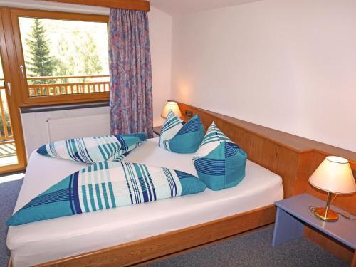 a bedroom with a bed with blue and white pillows at Apartment Erika by Interhome in Kappl