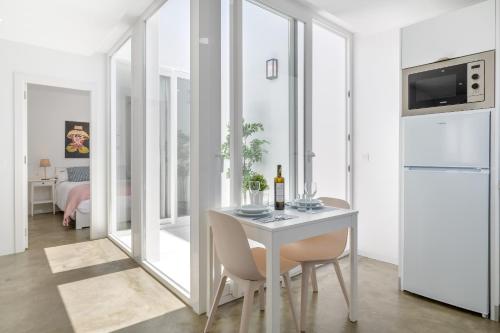 a white dining room with a table and a refrigerator at Las Rosas in Punta de Mujeres