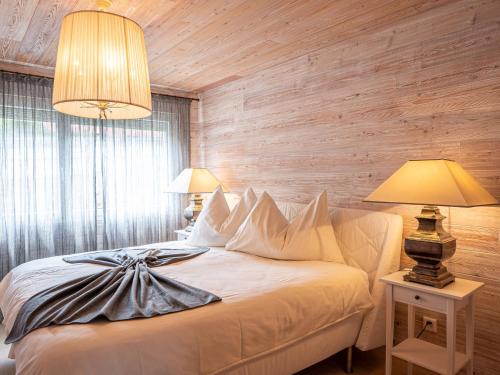 1 Schlafzimmer mit einem weißen Bett mit Holzwänden und 2 Lampen in der Unterkunft Apartment Chesa Sur Val 21 by Interhome in St. Moritz