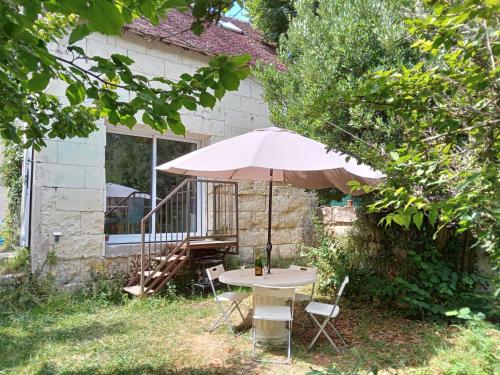 uma mesa com um guarda-chuva em frente a uma casa em Holiday Home La petite maison blanche by Interhome em Chissay-en-Touraine