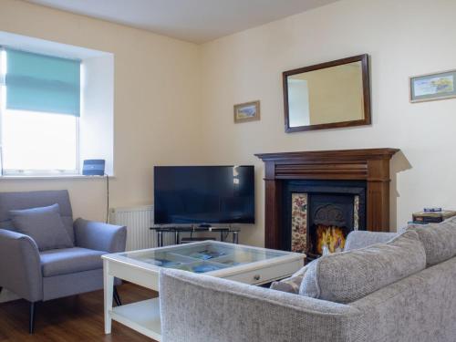 sala de estar con sofá, TV y chimenea en Holiday Home Keepers by Interhome, en Staffin