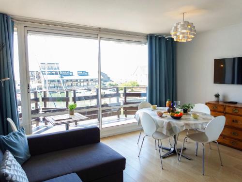 uma sala de estar com uma mesa e uma grande janela em Apartment Les Marinas by Interhome em Deauville