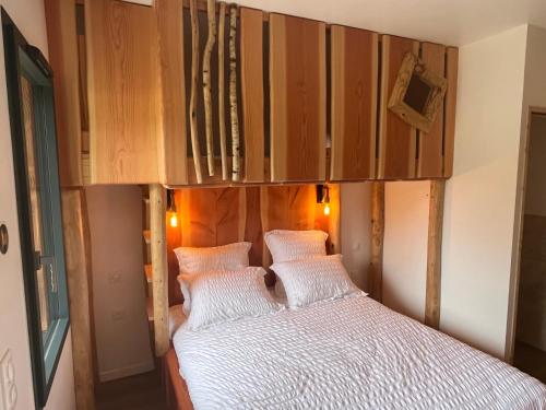 - une chambre avec un lit et une tête de lit en bois dans l'établissement LE DOMAINE DES CYGNES, à Lamballe