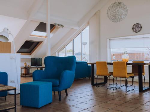 een woonkamer met blauwe stoelen en een tafel bij Apartment De Meerparel by Interhome in Uitgeest