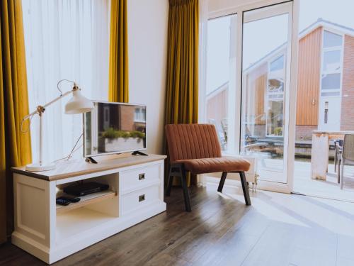 uma sala de estar com uma secretária, uma televisão e uma cadeira em Holiday Home De Meerparel-1 by Interhome em Uitgeest