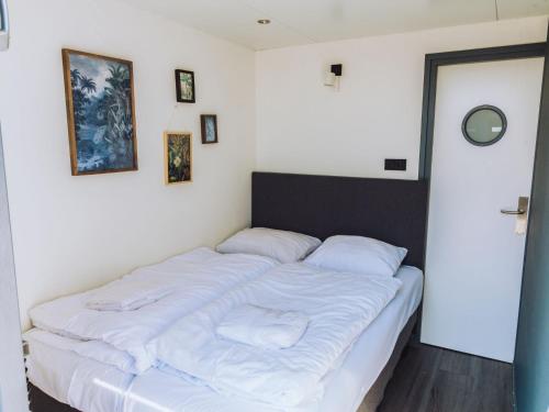 a bedroom with a bed with white sheets and pillows at Holiday Home De Meerparel-1 by Interhome in Uitgeest