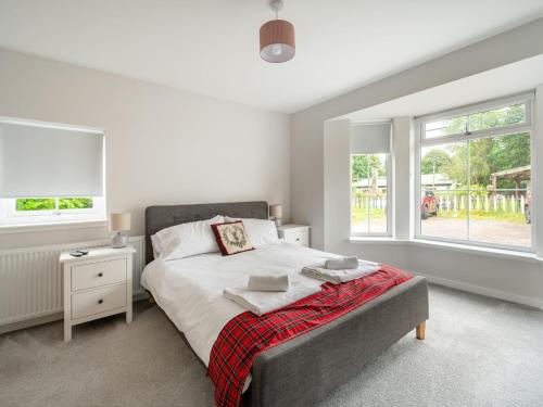 a bedroom with a bed and two windows at Holiday Home Loch Ness House by Interhome in Drumnadrochit