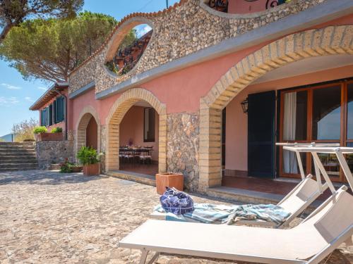 a house on the beach with a chair and a building at Holiday Home Sole by Interhome in Porto Santo Stefano