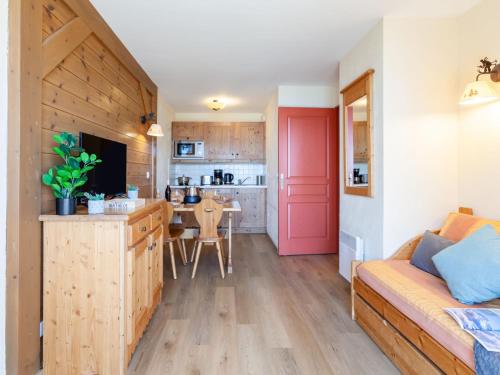 a living room with a red door and a kitchen at Apartment Les Alpages du Corbier-7 by Interhome in Le Corbier
