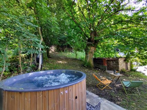 a large hot tub in a yard with a table and a chair at Apartment Locanda del Nibbio-2 by Interhome in Carriola