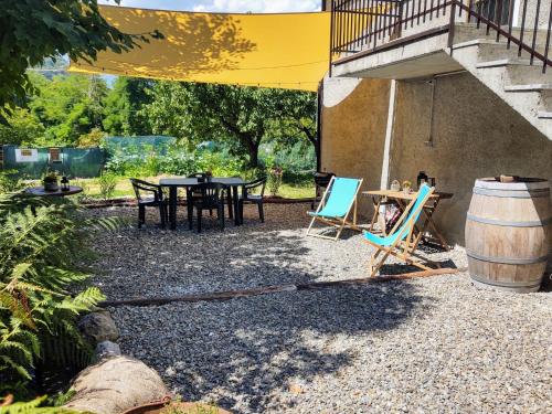 eine Terrasse mit einem Tisch, Stühlen und einem Fass in der Unterkunft Apartment Locanda del Nibbio-2 by Interhome in Carriola