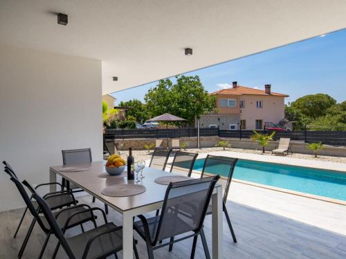 jadalnia ze stołem i krzesłami przy basenie w obiekcie Holiday Home Villa Palma by Interhome w mieście Pinezići