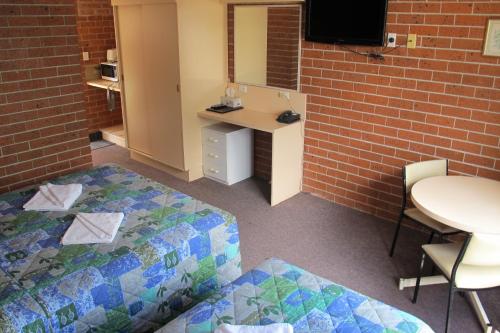 a room with two beds and a table and a mirror at Greenslopes Motor Inn in Brisbane
