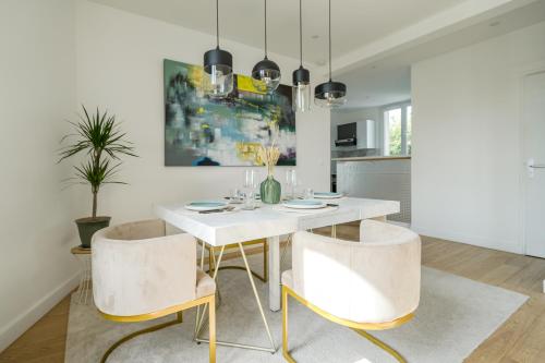 une salle à manger avec une table et des chaises blanches dans l'établissement The Nell house, à Vigneux-sur-Seine