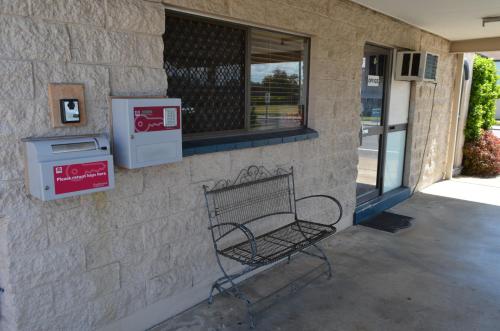 a bench sitting in front of a building with a window at Welcome Home Motel Rockhampton in Rockhampton